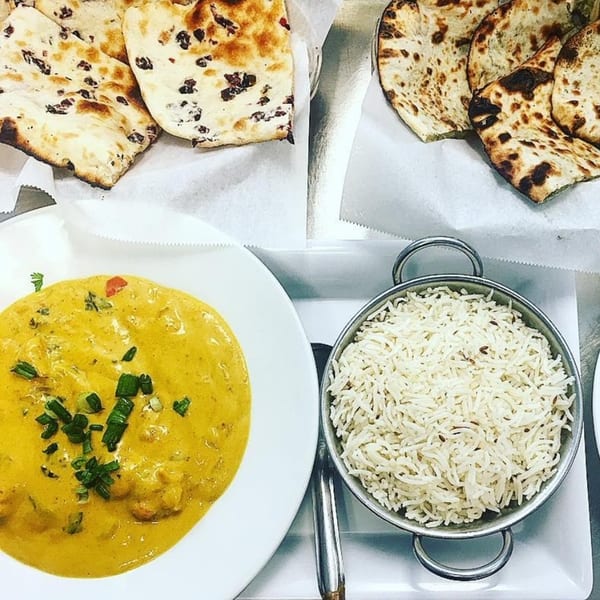 Love Curry Indian Cuisine: creamy yellow curry, white rice, and two baskets of naan bread.